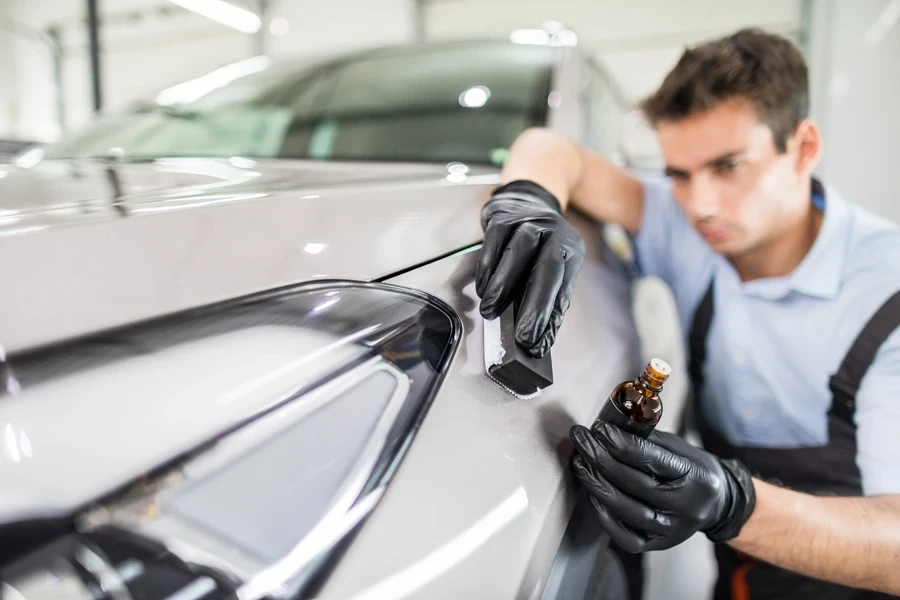 A person rubbing a brush on a car