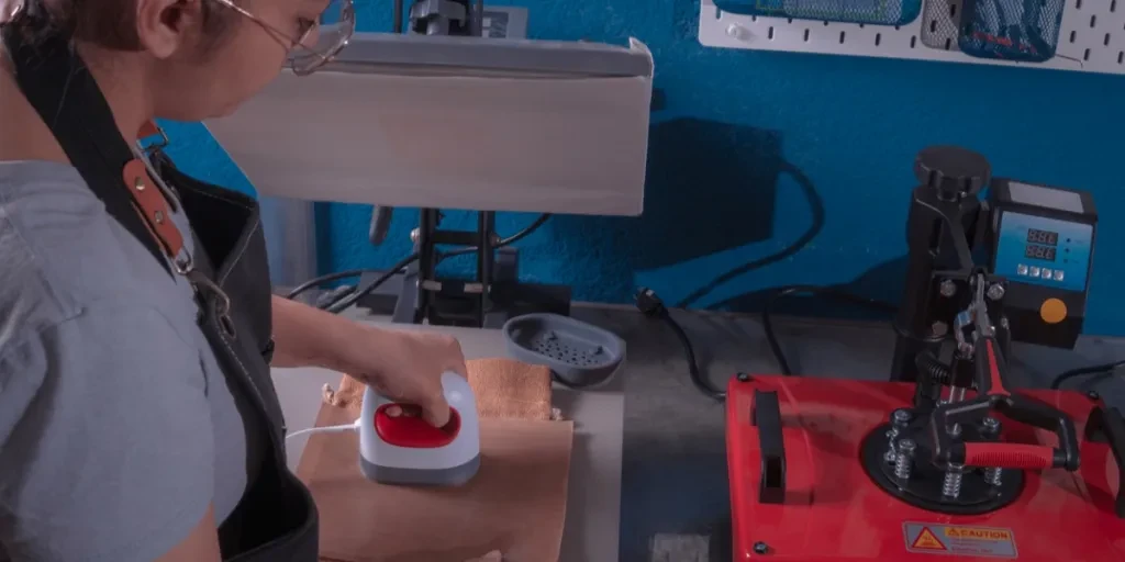 A woman using a mini heat press in her workshop