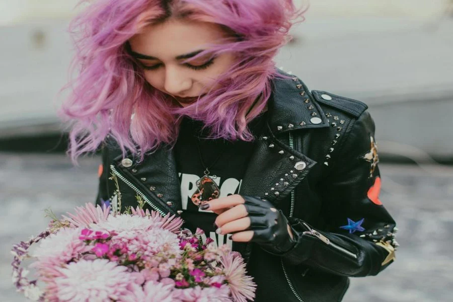 A woman with pink hair wearing a studded jacket