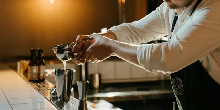 Bartender squeezing fresh lime juice into a shaker for a cocktail at a stylish bar