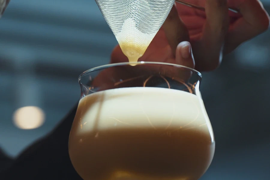 Bartender using fine mesh juice strainer to make cocktail