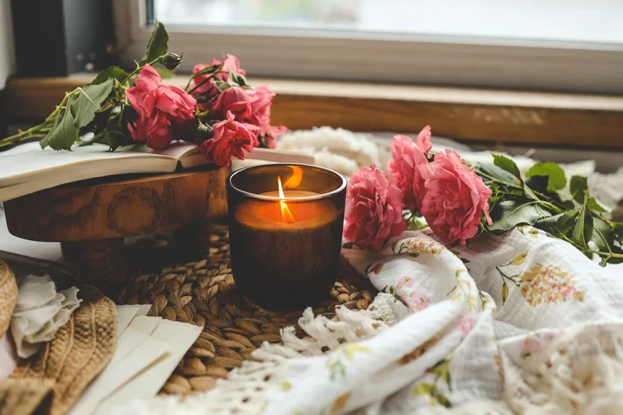Burning candle with books and roses