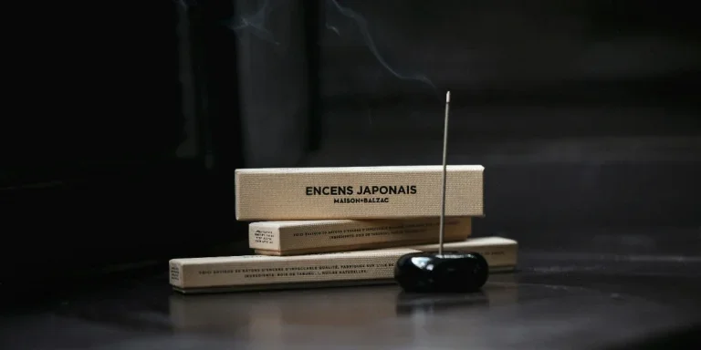 Burning incense stick in front of brown boxes