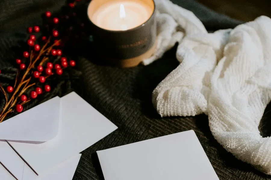 Vela encendida sobre una mesa junto a manteles y papeles.