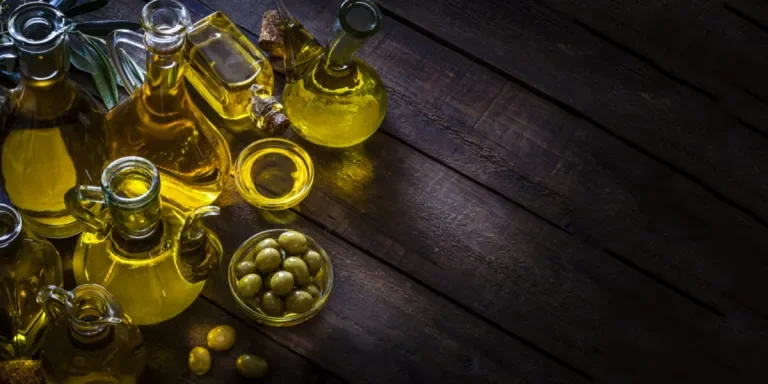 Collection of glass olive oil bottles on wooden table