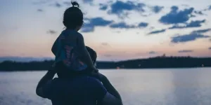 Father and daughter looking out at a lake