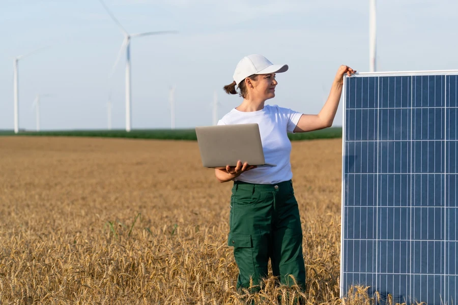 Female technician standing with laptop next to small solar panel