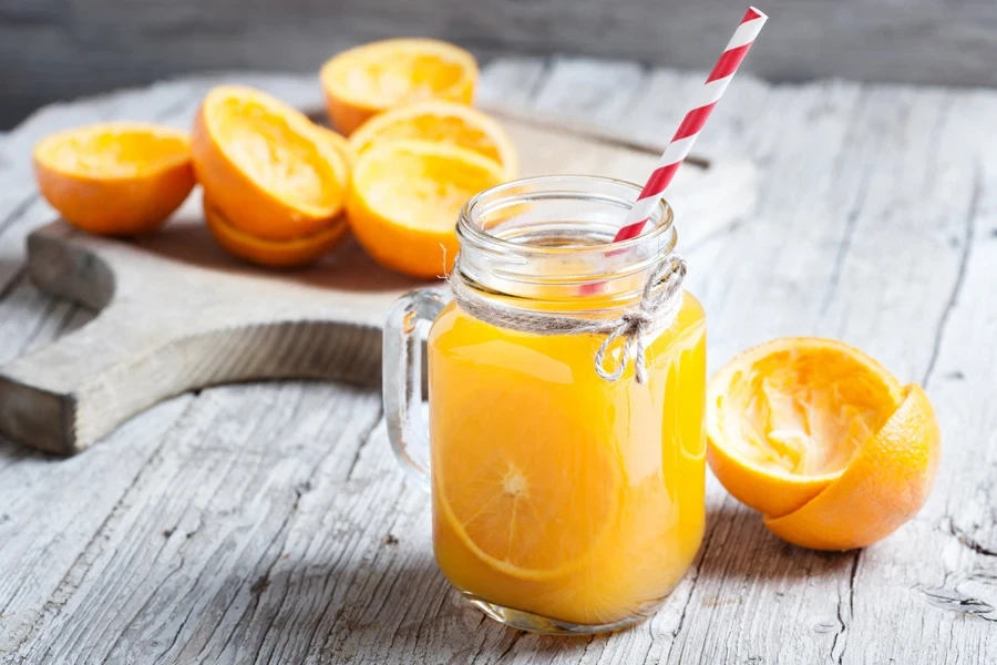 Fresh orange juice in mason jar with straw