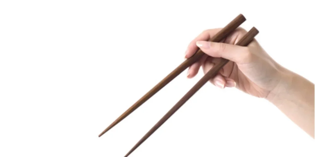 Manos sosteniendo un par de palillos de madera