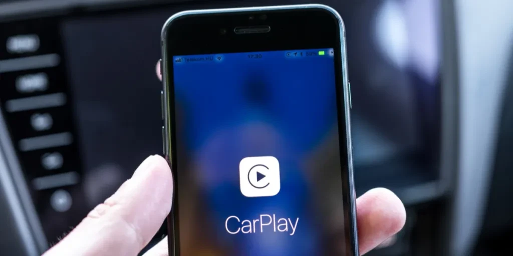 Hands holding a phone connected to CarPlay