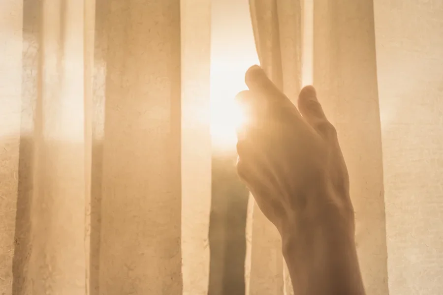 Hands opening curtains, revealing sunlight