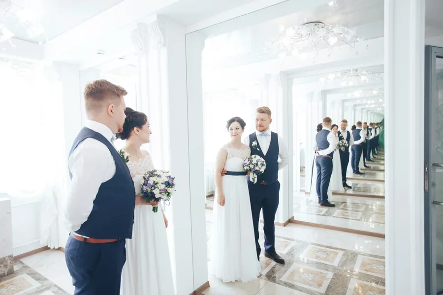 Счастливая молодожены стоят между двумя зеркалами с бесконечным отражением