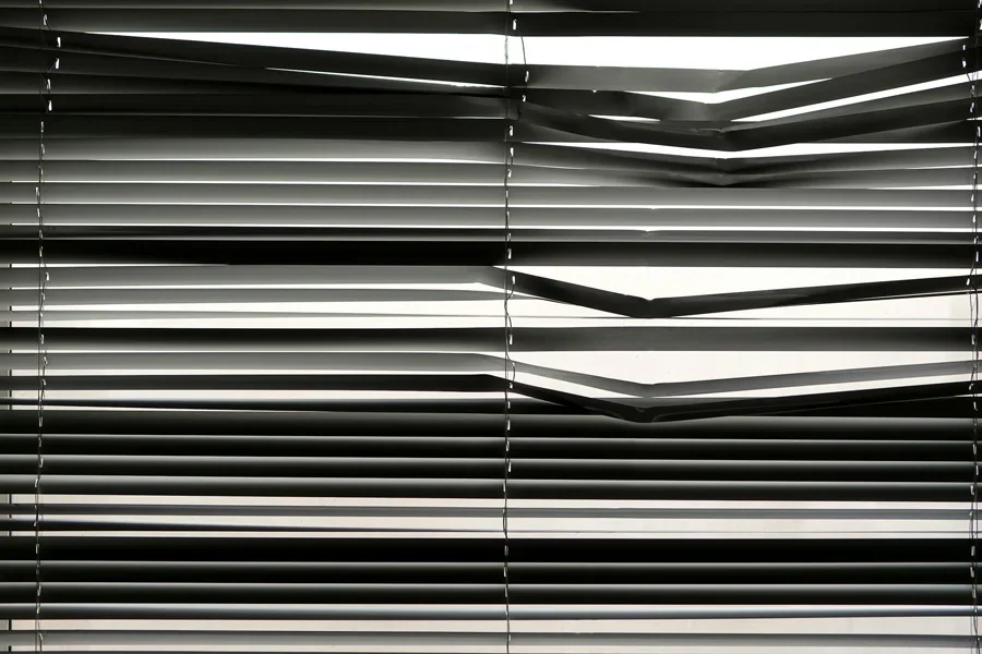 Horizontal venetian blinds creating a shadow pattern indoors with strong sunlight