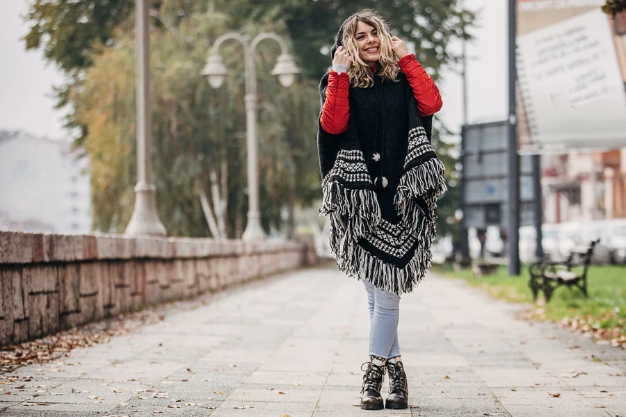 Lady wearing raw-edge poncho, skinny jeans, and leather boots