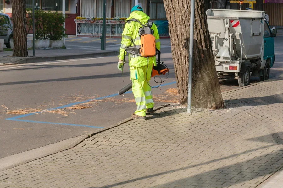Landscaper blowing off leaves using a backpack electric leaf blower
