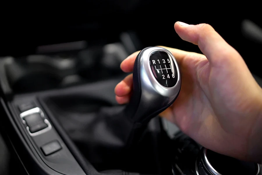 Male hand holding manual gearbox in car, test drive of new automobile