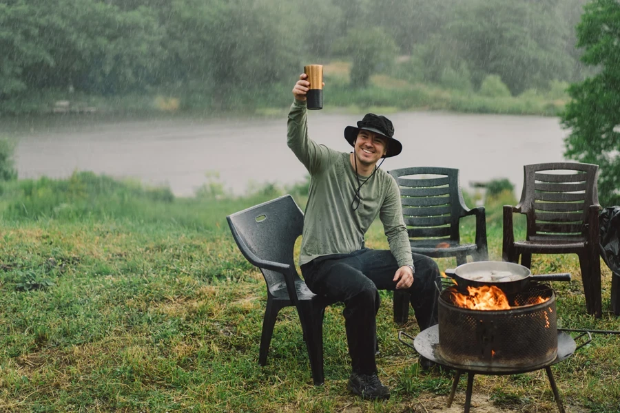 Man camping in the rain wearing solar panel hat
