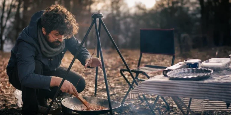 Hombre preparando comida en una cocina de camping.