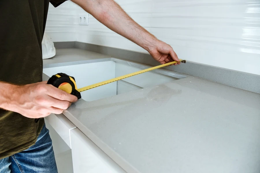 Man using measuring tape alongside of kitchen sink