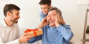 Mature son and grandson gifting granddad a present