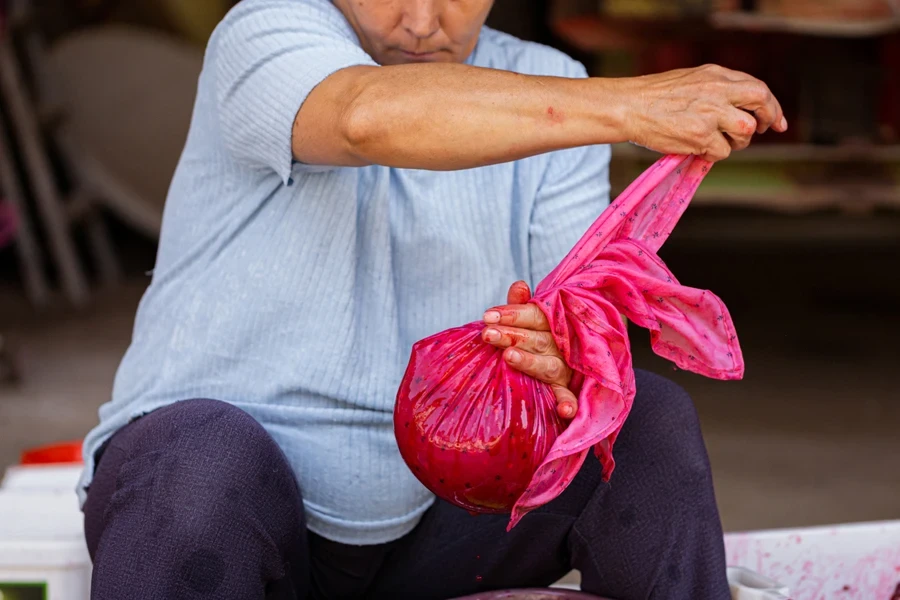 Mature woman using nut milk bag with cherries