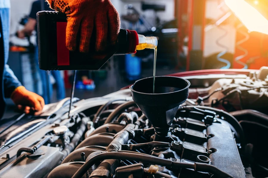 Mechanic pouring synthetic oil into a modern car