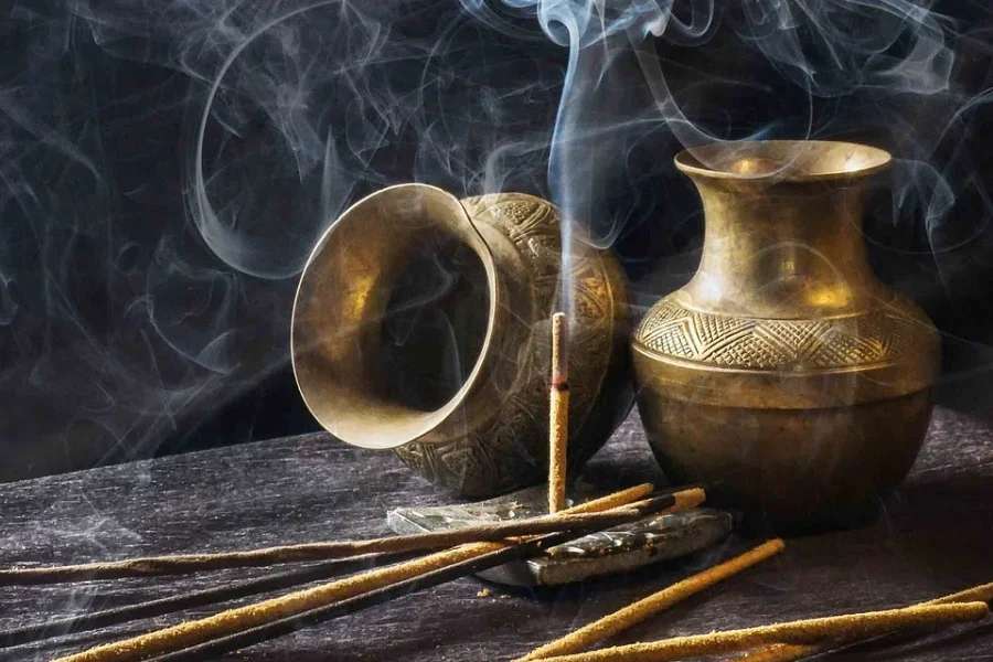 Räucherstäbchenhalter aus Metall neben Vasen