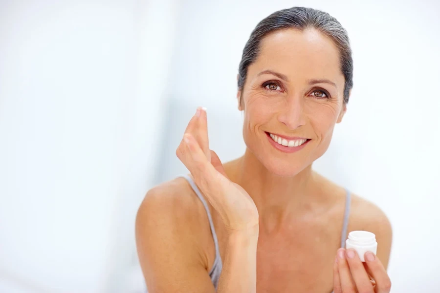 Middle aged woman applying thick cream to wrinkles