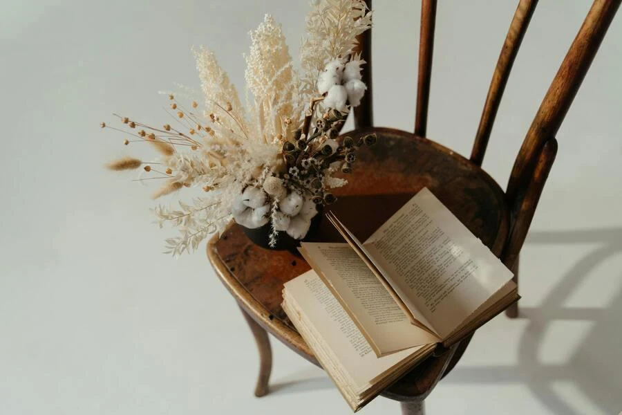 Open book and flowers on a wooden chair