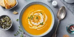 Orange soup with spoon and bread