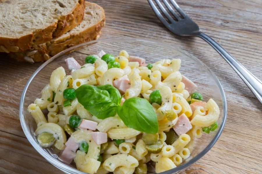 Pasta salad in a glass bowl on wooden table