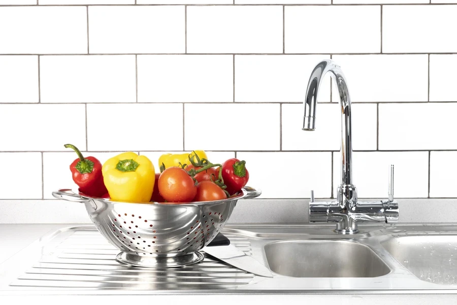 Peppers in colander next to double stainless steel sink