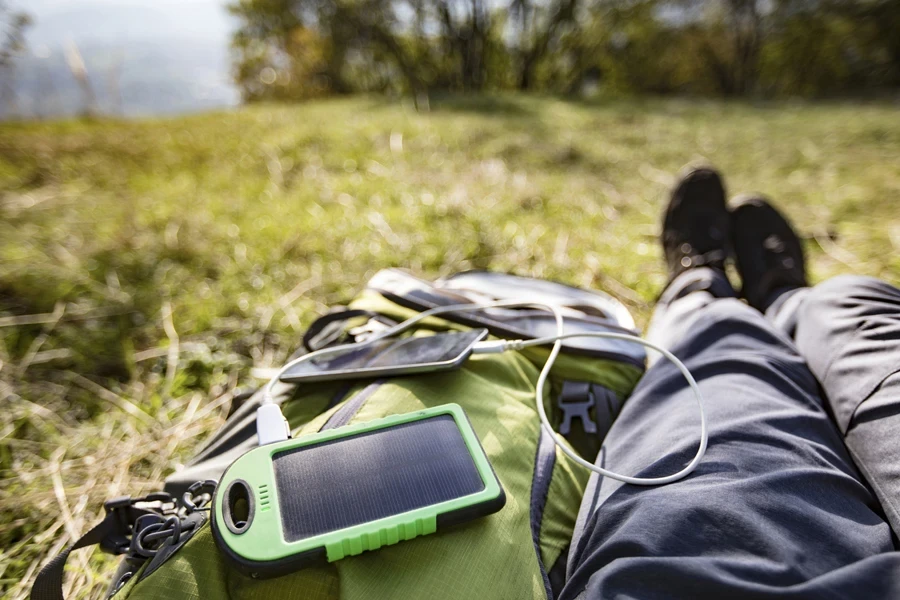 Person charging electronic devices while sitting on grass