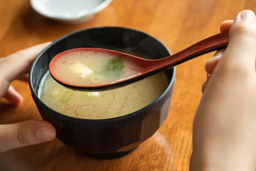 Person drinking miso soup with a melamine spoon