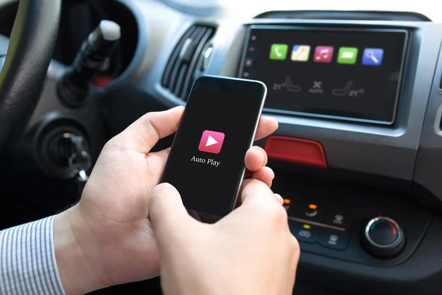 Person holding smartphone connected to car player