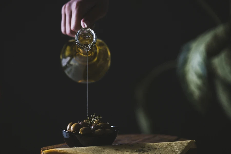 Person pouring small amount of olive oil on olives