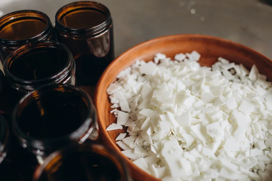 Soy wax in a wooden bowl next to glass jars
