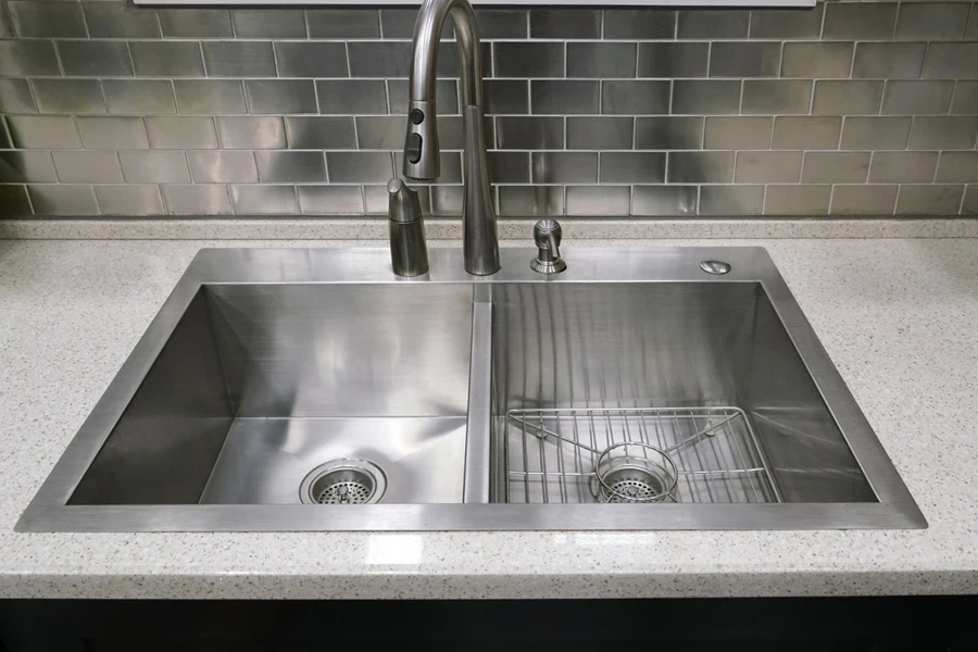 Stainless steel sink with metallic tiled backdrop under window