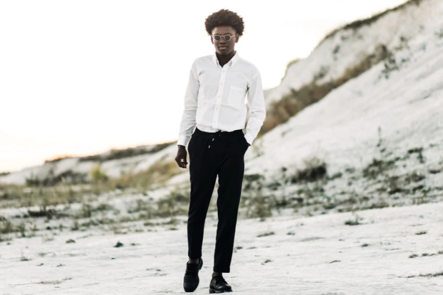 Stylish man in white shirt, black drawstring pants, and sunglasses.
