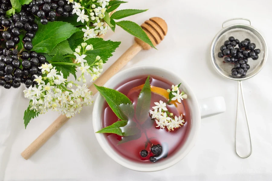 Tea with fresh fruits in mesh strainer among other parts