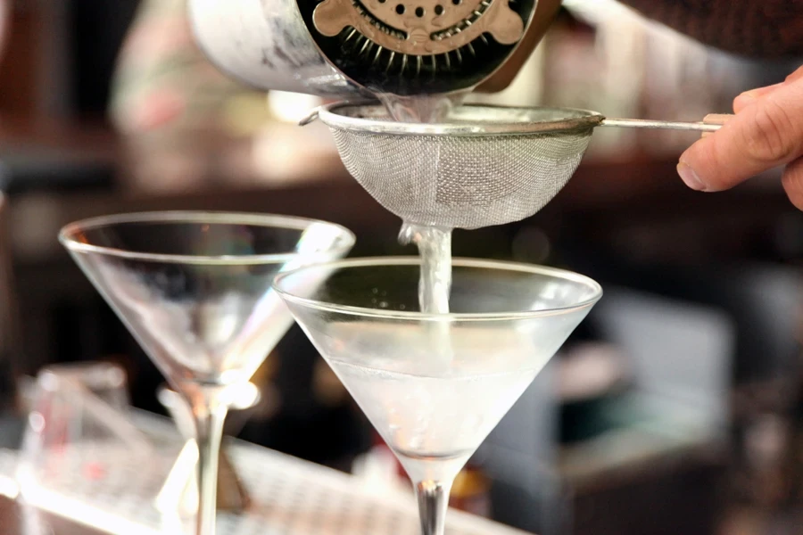 Two cocktails being made using a fine mesh strainer