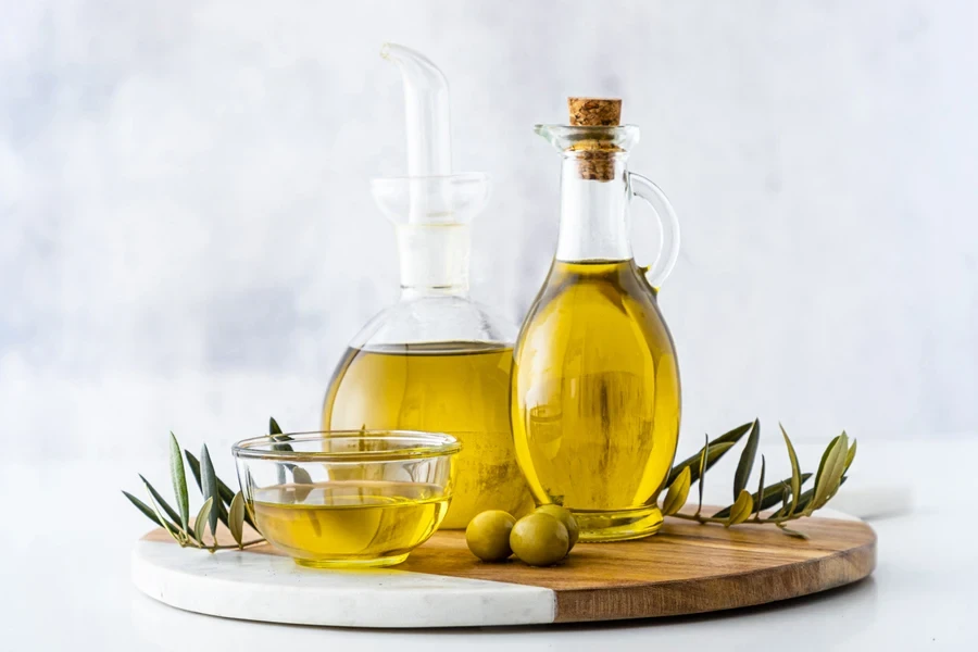Two different shaped clear glass oil bottles on wooden tray