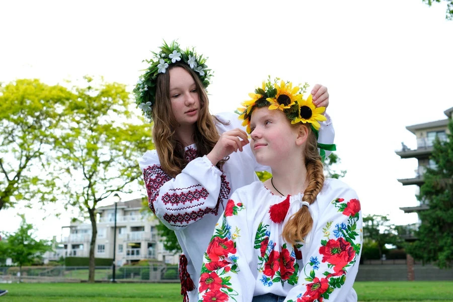 Two girls wearing embroidered floral tops