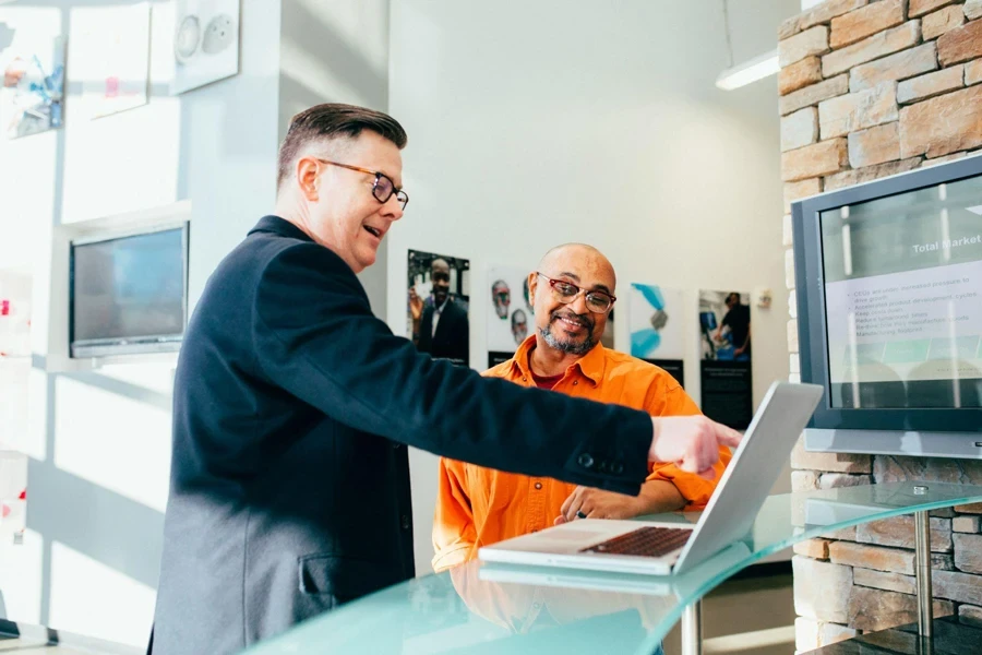 Two men looking at a white laptop