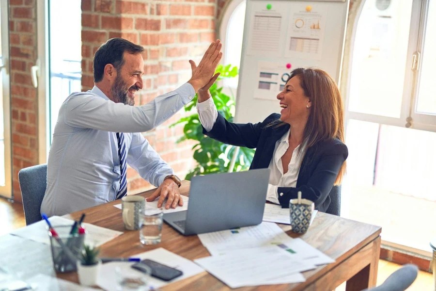 Two middle-aged business workers smiling and high-fiving