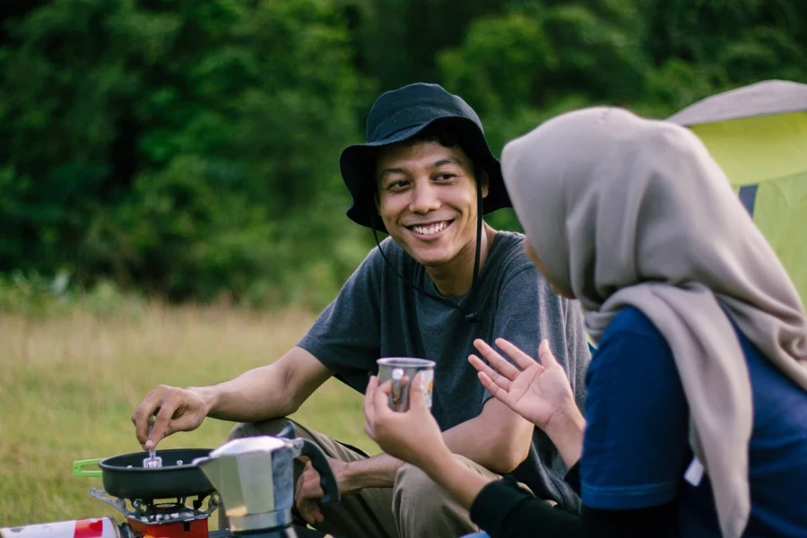 Two people cooking food on camping stove outdoors