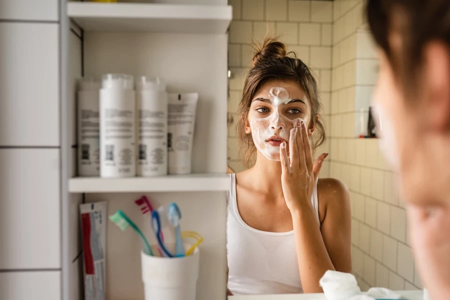 Woman applying large amount of face cream in mirror