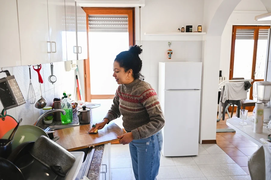Woman cleaning large wooden sink cover in kitchen
