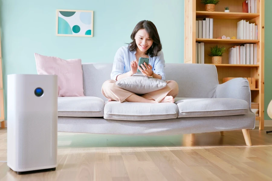 Woman sitting using air purifier while using a mobile phone