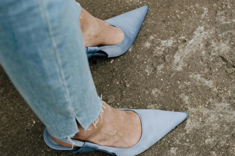 Woman wearing a pair of blue pointed slingback mules